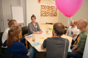 Eine Referentin diskutiert mit den Teilnehmern des Workshops an einem großen Tisch.